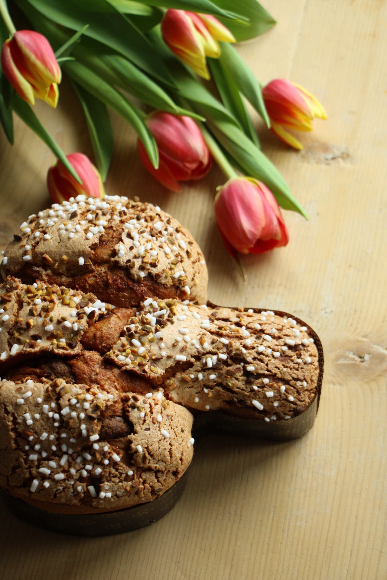 Colomba pasquale artigianale con granella tra tulipani