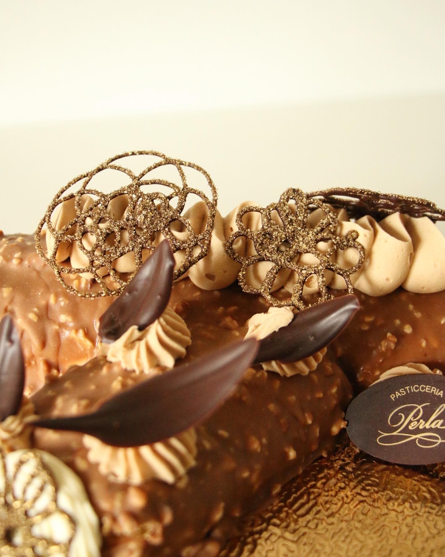 Tronchetto di Natale con riccioli di cioccolato e decorazioni dorate
